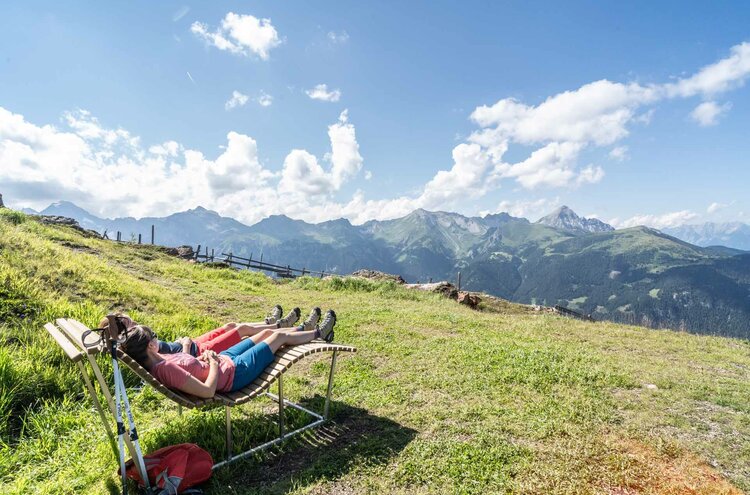 Wanderer beim Entspannen auf Holzliegen in Wiese im Wipptal